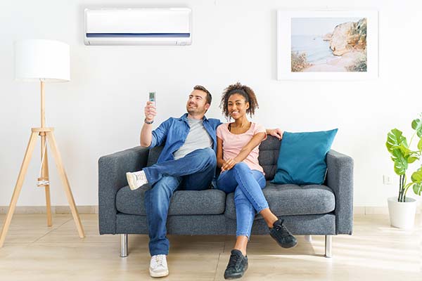 Two individuals sitting comfortably on a couch in a well-ventilated room