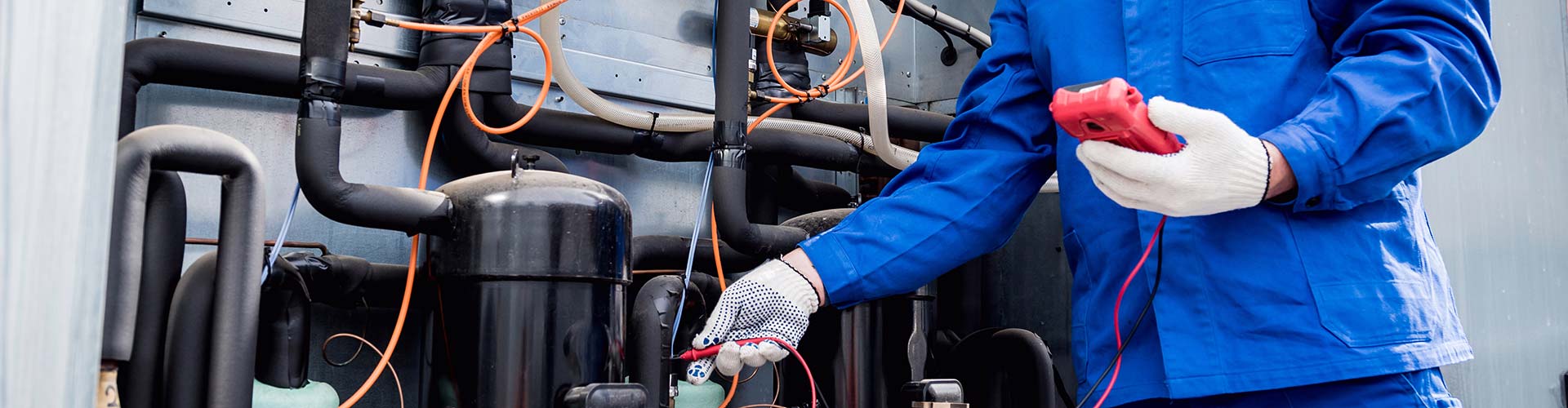 A professional in a blue uniform holding an HVAC repair tool