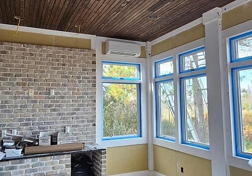 A room featuring a brick fireplace and large windows for comfort